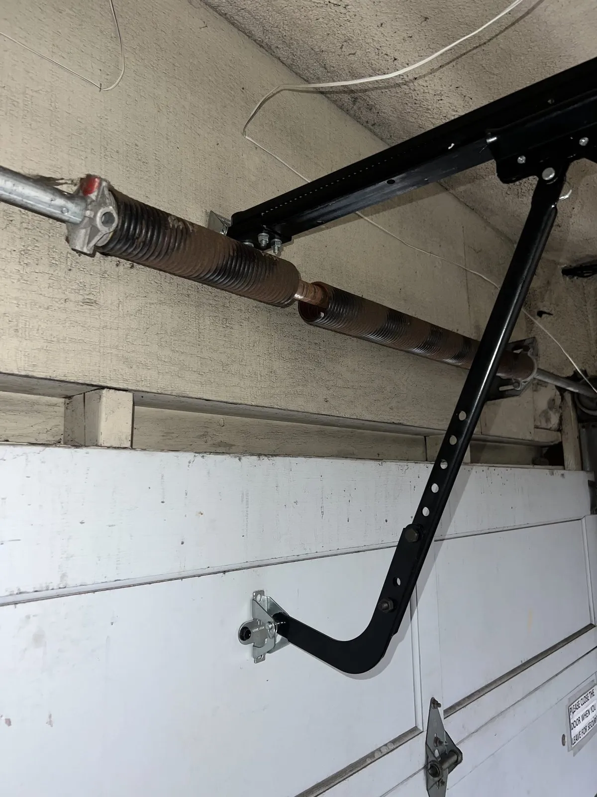 A snapped torsion spring still mounted above a garage door